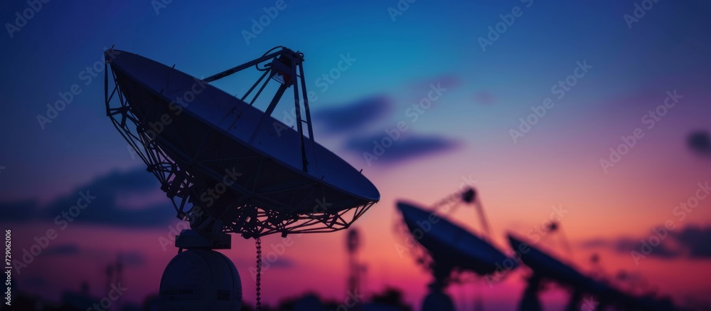 Artistic decoration using selective focus on silhouetted satellite dishes or radio antennas against a night sky during sunset. Artistic decoration using selective focus on silhouetted satellite dishes or radio antennas against a night sky during sunset.