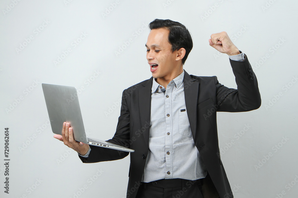 Happy asian indonesian business man in suit holding laptop computer on isolated background Happy asian indonesian business man in suit holding laptop computer on isolated background