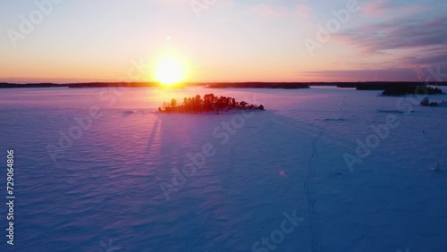 Drone shot over snowy ice and a isle, winter evening in the finnish archipelago photo