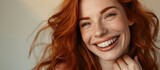 Happy and in love, a smiling woman with red hair poses elegantly with one hand near her heart and the other extended forward.