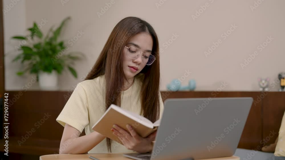 Studious Asian young woman with glasses, reading, laptop for research, earnest educational effort. Focused female student with book, laptop beside, immersed in study, peaceful indoor setting Studious Asian young woman with glasses, reading, laptop for research, earnest educational effort. Focused female student with book, laptop beside, immersed in study, peaceful indoor setting