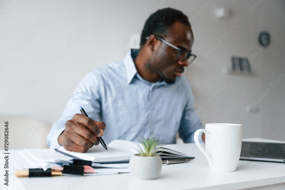 Doing some paperwork. Businessman is in the office by laptop Doing some paperwork. Businessman is in the office by laptop