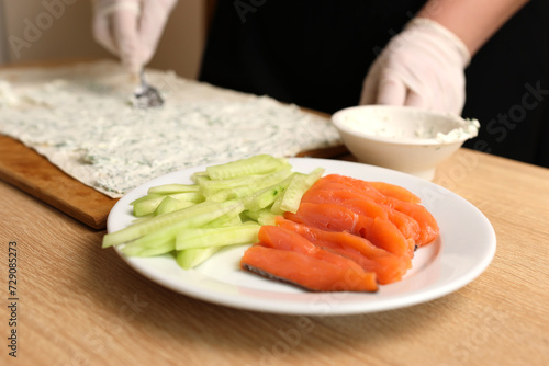 A layer of prepared cheese is applied to pita bread. Preparation of roll with fish and vegetables