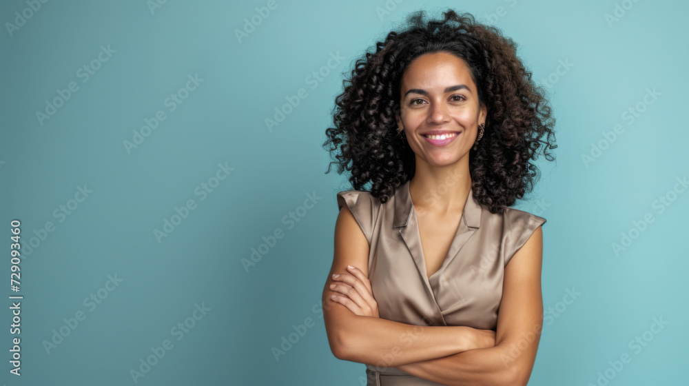 woman with curly hair is smiling at the camera, standing with her arms crossed in front of a light blue background woman with curly hair is smiling at the camera, standing with her arms crossed in front of a light blue background