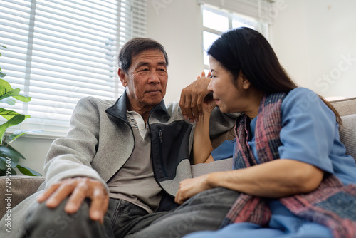Older couples sit and chat and head over each other relaxed and happy on sofa at home on weekday in comfortable