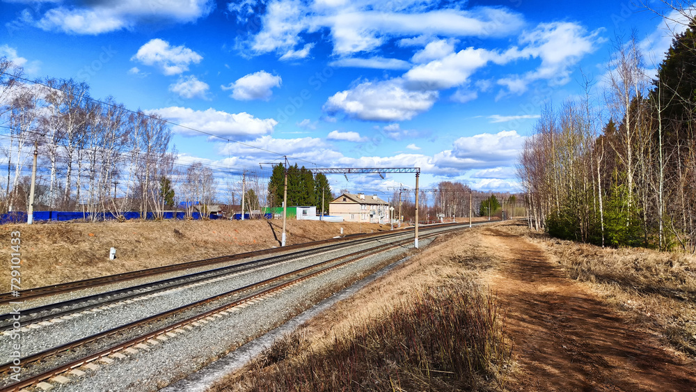 Railway track in the spring forest with blue sky. The concept of travel and trip