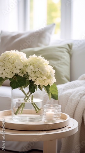 	
Bouquet of hortensia flowers and glass bowls on modern wooden coffee table and cozy sofa with pillo