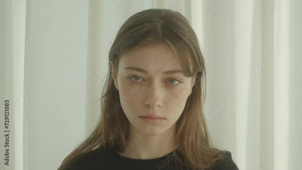 An expressionless young woman looks directly into the lens. An expressionless young woman looks directly into the lens.