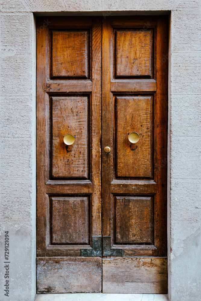 Elegant old double door entrance of building in Europe. Vintage wooden doorway of ancient stone house. Simple brown wood door. Architecture in Italy.