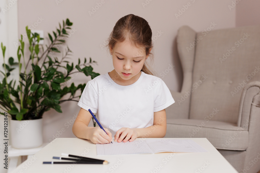 Little girl sitting at table and doing homework Little girl sitting at table and doing homework