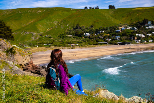 hiker girl enjoying a sunny day at godley head walkaway near christchurch, canterbury, new zealand; walking alongside the paradise coastline of pacific ocean photo