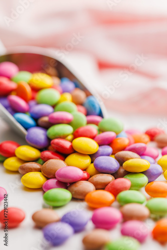 Colorful sweet candies in scoop on white table.
