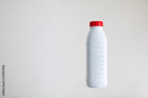 Photos White opaque plastic bottle with a red cap isolated on white background, no labe