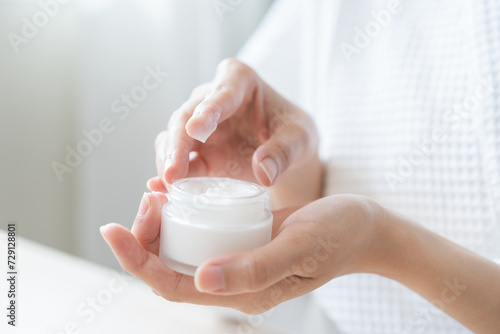 Obraz na plátne Health care, beauty asian young woman in bathrobe, towel after shower bath, spa relax at home, use finger putting take out moisturizer cream from jar
