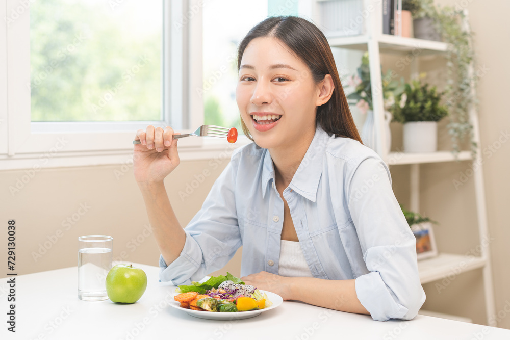 Diet concept, happy asian young woman hand use a fork to prick tomato, fresh vegetable or green salad, eat nutrition food on table at home, low fat to good body. Girl getting weight loss for healthy. Diet concept, happy asian young woman hand use a fork to prick tomato, fresh vegetable or green salad, eat nutrition food on table at home, low fat to good body. Girl getting weight loss for healthy.