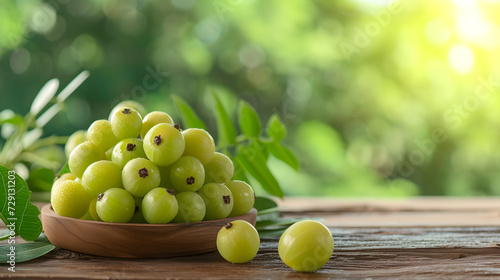 Fresh Amla (Indian gooseberry) fruits on wooden table with amla plant background