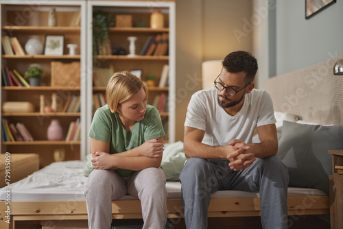 Fotografie Young couple sitting on bed discussing marital problems