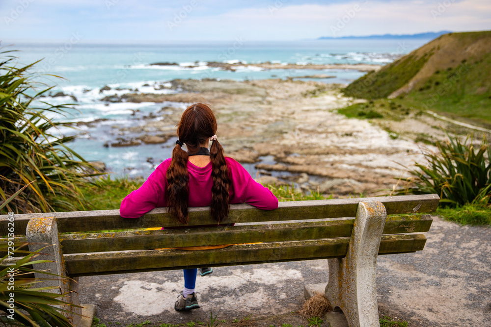 relaxed girl admiring the panorama of kaikoura peninsula from the top of a cliff; north canterbury, new zealand