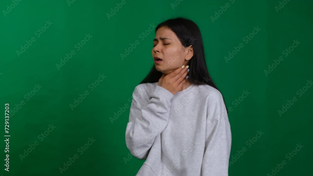 Health concern. Woman in a studio portrait expresses discomfort, indicating a sore throat, as she battles illness and seeks relief from the flu or infection Health concern. Woman in a studio portrait expresses discomfort, indicating a sore throat, as she battles illness and seeks relief from the flu or infection