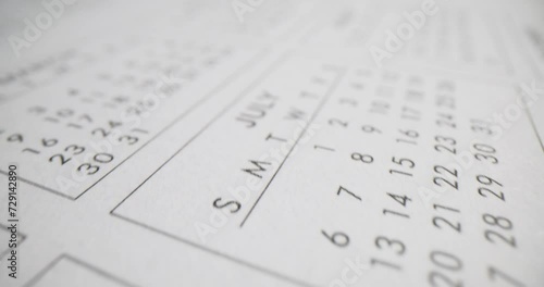 Different months page of notepad with annual calendar on table in office
