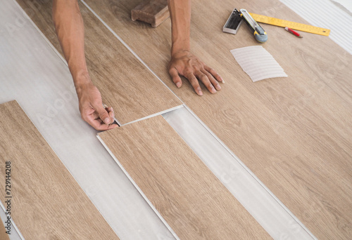 A technician is cutting luxury vinyl floor tiles with a cutter to lay the floor before placing it on the leveling foam. © SimpleBen.CNX