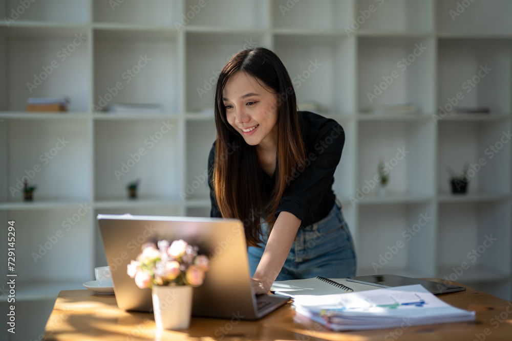 Cheerful businesswoman reviewing a financial report next to her laptop in a well-lit office space.. Cheerful businesswoman reviewing a financial report next to her laptop in a well-lit office space..
