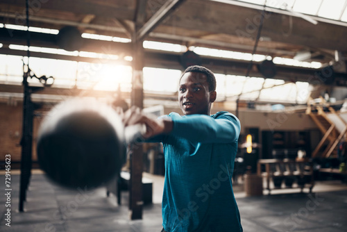 Smiling young man swinging a kettlebell during a gym workout photo