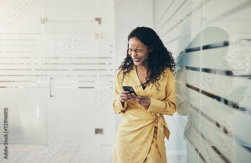 Businesswoman laughing at a text during a work break in an office photo