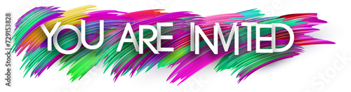 You are invited paper word sign with colorful spectrum paint brush strokes over white.