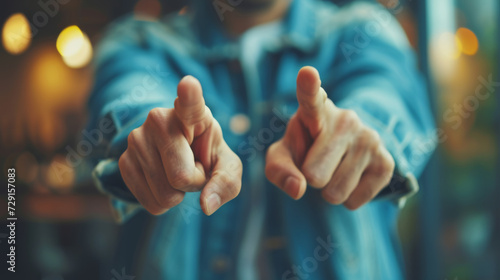 person in a denim jacket is pointing directly at the camera, with the focus on the pointing finger and the background blurred.