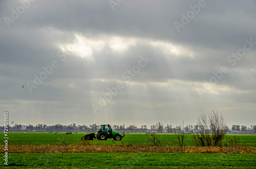 Farmer on a tractor working on a field under a dramatic sky near Schoonhoven, The Netherlands