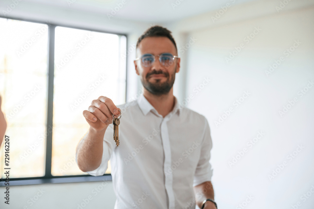 Fototapeta premium Realtor is standing and holding keys for new apartment