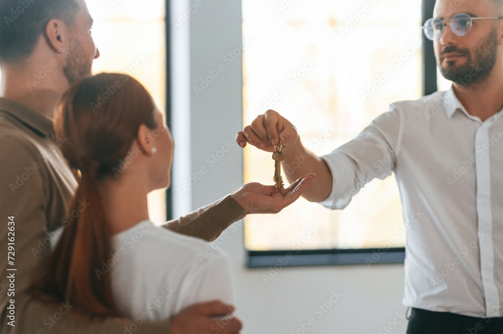 Customers bought the place, receiving the keys. Realtor shows an apartment to a young couple Customers bought the place, receiving the keys. Realtor shows an apartment to a young couple