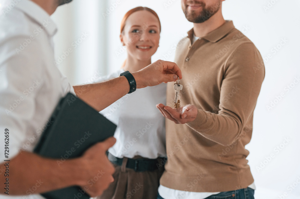 Obraz premium Customers bought the place, receiving the keys. Realtor shows an apartment to a young couple