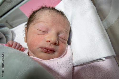 On her first day of life, a newborn baby girl wears a pink hospital ID bracelet on her hand photo