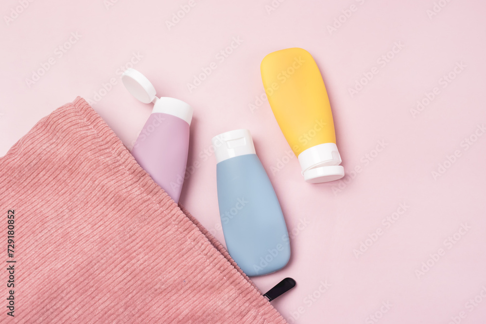 Compact toiletry bag with colored cosmetic jars on light pink background top view copy space Compact toiletry bag with colored cosmetic jars on light pink background top view copy space