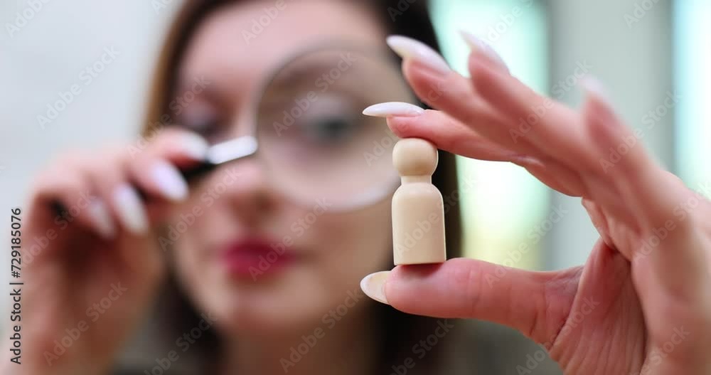 Woman boss or HR manager looks at wooden figure through magnifying glass Woman boss or HR manager looks at wooden figure through magnifying glass