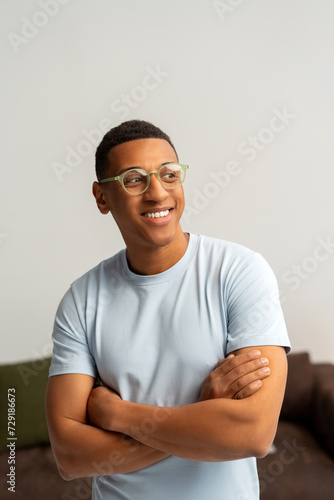 Smiling attractive young Latin man wearing casual clothes, stylish eyeglasses with crossed arms © Maria Vitkovska
