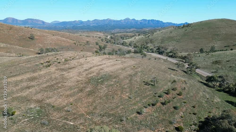 Drone above green terrain landscape with a road on a sunny day with blue sky Drone above green terrain landscape with a road on a sunny day with blue sky