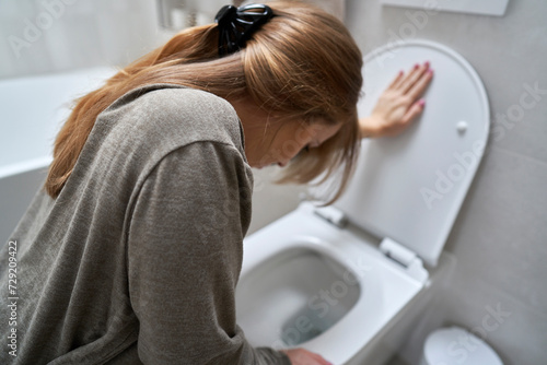 Obraz na plátně Woman bending over toilet and having a nausea