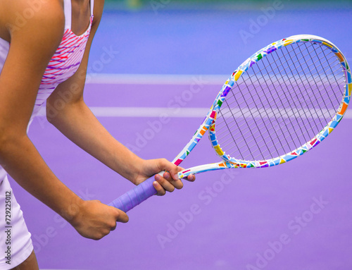 close-up of the hands of a tennis player holding a tennis racket on a tennis court on a summer day