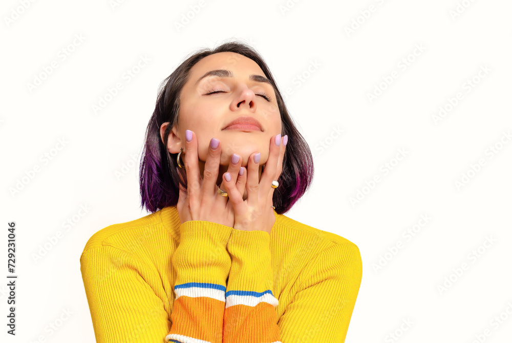 Dreamy happy optimistic woman keeps eyes closed, smiles gently. Yellow jumper, white background. Dreamy happy optimistic woman keeps eyes closed, smiles gently. Yellow jumper, white background.