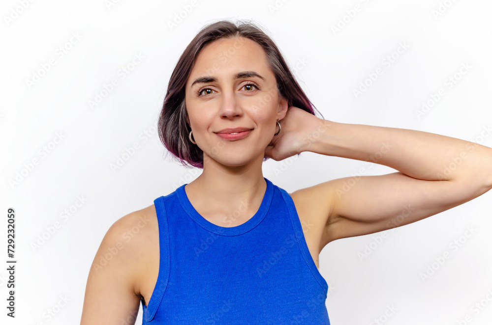 Young woman in blue sleeveless dress poses in the studio on a white background. Hand near head. Young woman in blue sleeveless dress poses in the studio on a white background. Hand near head.