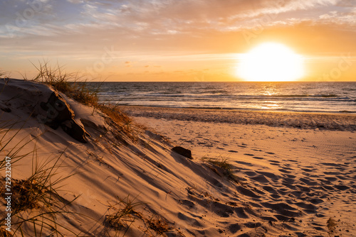 Horizontal crop of a golden sunset over the dune at the beach in Henley Beach, South Australia. © trappy76