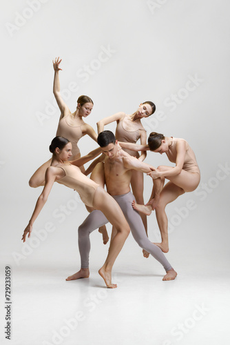 Talented artistic young people, man and women, ballet dancers performing against white studio background. Baller art, aesthetics. Concept of classical dance, modern style, inspiration