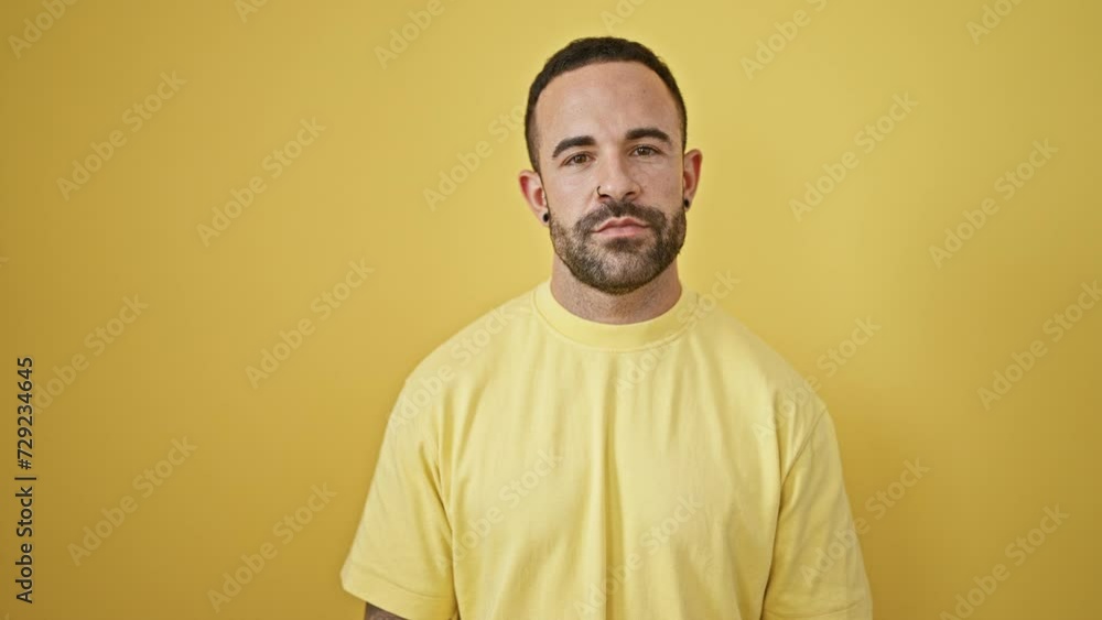 Portrait of a handsome bearded man with yellow shirt posing against a vibrant yellow background. Portrait of a handsome bearded man with yellow shirt posing against a vibrant yellow background.