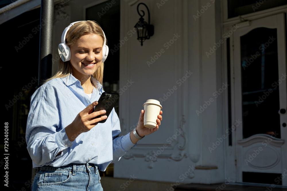 Fototapeta premium A girl in headphones and with a phone on the street.