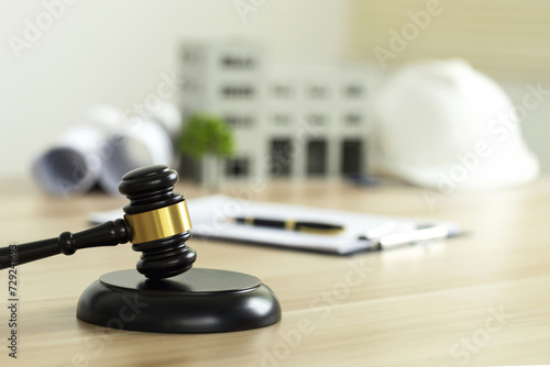Labor and Construction law concept. judge gavel on building blueprint plans with a safety helmet and building model. Paper sheet with pen on wooden table. Agreement on construction law. home insurance photo