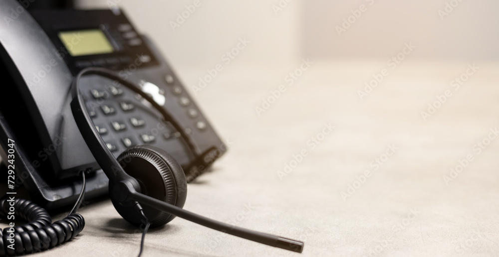 close up black headset with telephone at office background in operation room to communicate with provider or response client for call center and hotline service concept close up black headset with telephone at office background in operation room to communicate with provider or response client for call center and hotline service concept