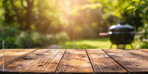 empty wooden table on blurred garden background with barbecue grill in summer photo